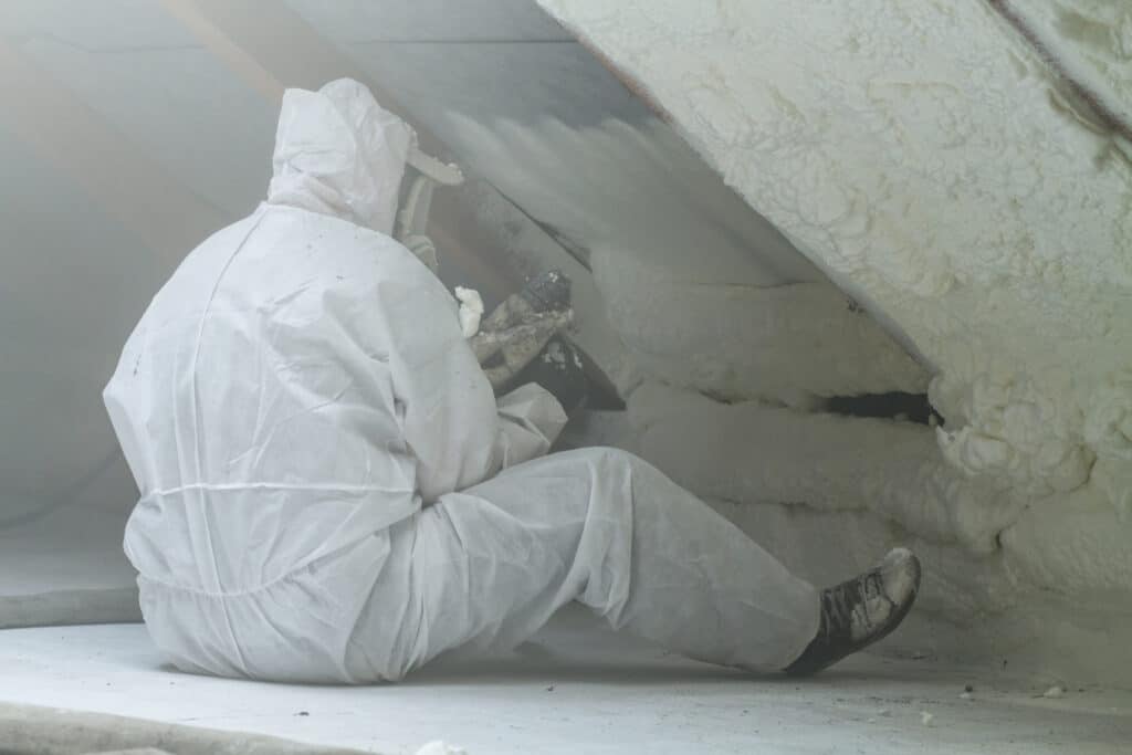 Worker applying spray foam insulation to walls